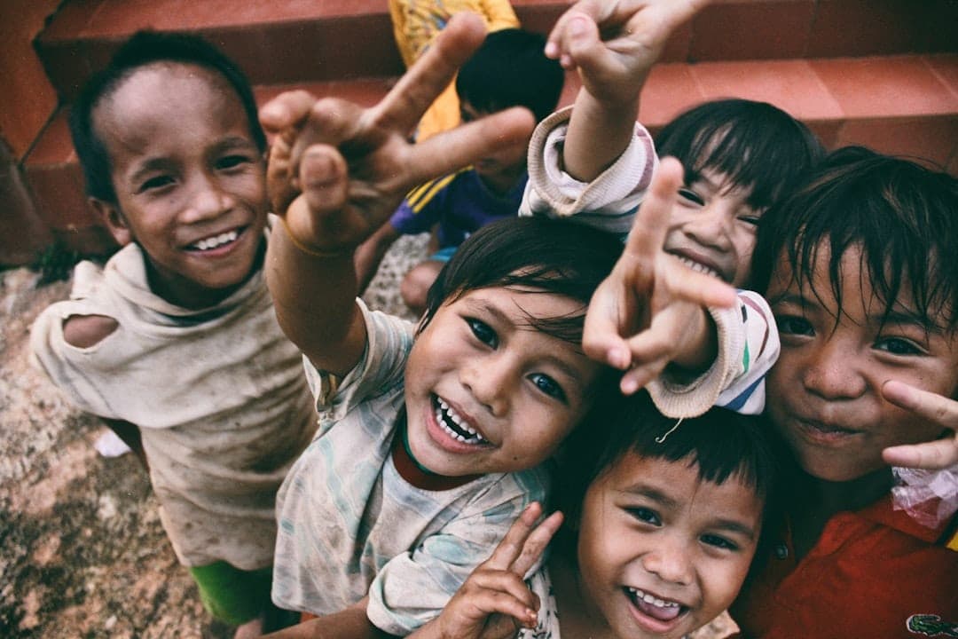 A group of smiling children flashing peace signs at the camera