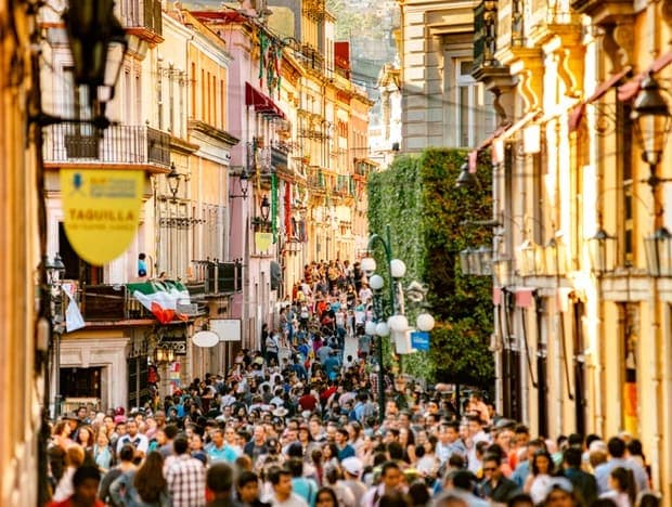 A lively crowded pedestrian street lined with colorful historic buildings